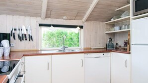 Une cuisine avec des meubles en bois, un lave-vaisselle Bosch et une fenêtre donnant sur un paysage verdoyant.