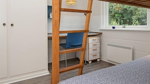 A bedroom with a wooden ladder desk, a blue chair, a white dresser, and a window with a view of greenery. - Enticing Holiday Home in Jutland near Sea (Aalbaek)
