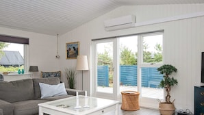 A modern living room with a grey sofa, a white coffee table, and a potted plant. - Enticing Holiday Home in Jutland near Sea (Aalbaek)