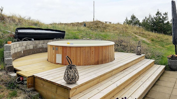 A wooden deck with a hot tub, steps, and outdoor furniture. - Enticing Holiday Home in Jutland near Sea (Aalbaek)