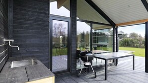 An outdoor patio with a grill, a table, and a sink. - 14 Person Holiday Home in Vaeggerlose (Vaeggerlose)