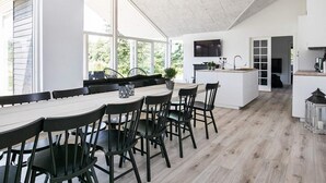 Une cuisine moderne dotée d’un grand îlot central, de chaises noires et d’une table à manger.