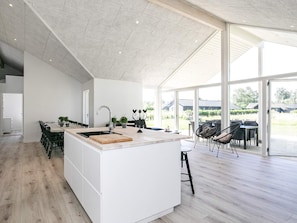 A modern kitchen with a large island, a dining area with chairs, and a view of the outdoors.