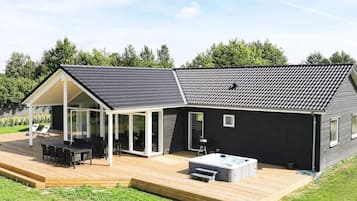 A modern house with a deck, a hot tub, and a covered patio area.