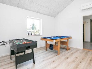 A room with a foosball table, a pool table, and a window with a view of trees. - 4 Star Holiday Home in Vaeggerlose (Vaeggerlose)