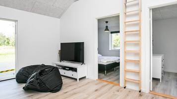A modern bedroom with a TV, bed, and a ladder leading to a balcony.