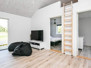 A modern bedroom with a TV, bed, and a ladder leading to a balcony. - 4 Star Holiday Home in Vaeggerlose (Vaeggerlose)