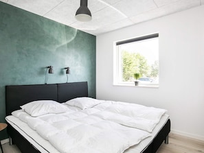 A modern bedroom with a large bed, two bedside lamps, a window with a view of trees, and a ceiling light. - 4 Star Holiday Home in Vaeggerlose (Vaeggerlose)