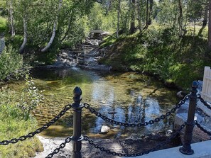 Una fuente de agua natural con un puente de piedra y una cerca de alambre.