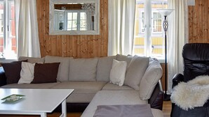 A cozy living room with a sectional sofa, a small table, a black leather chair, and a large mirror on the wall. - Holiday Home in Bjorli (Lesja)