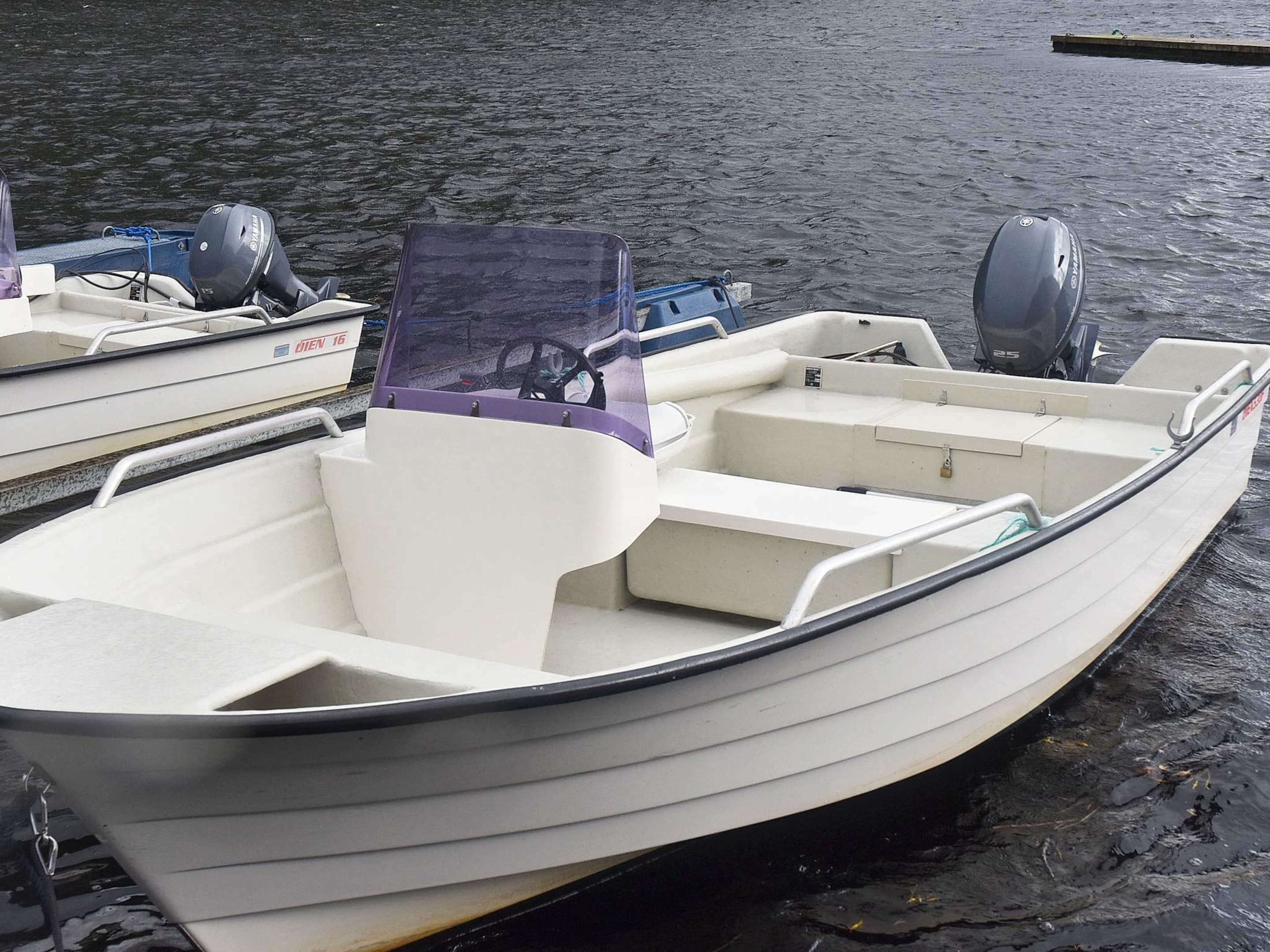 Ein kleines Motorboot mit Kabine, zwei Außenbordmotoren und Steuer.