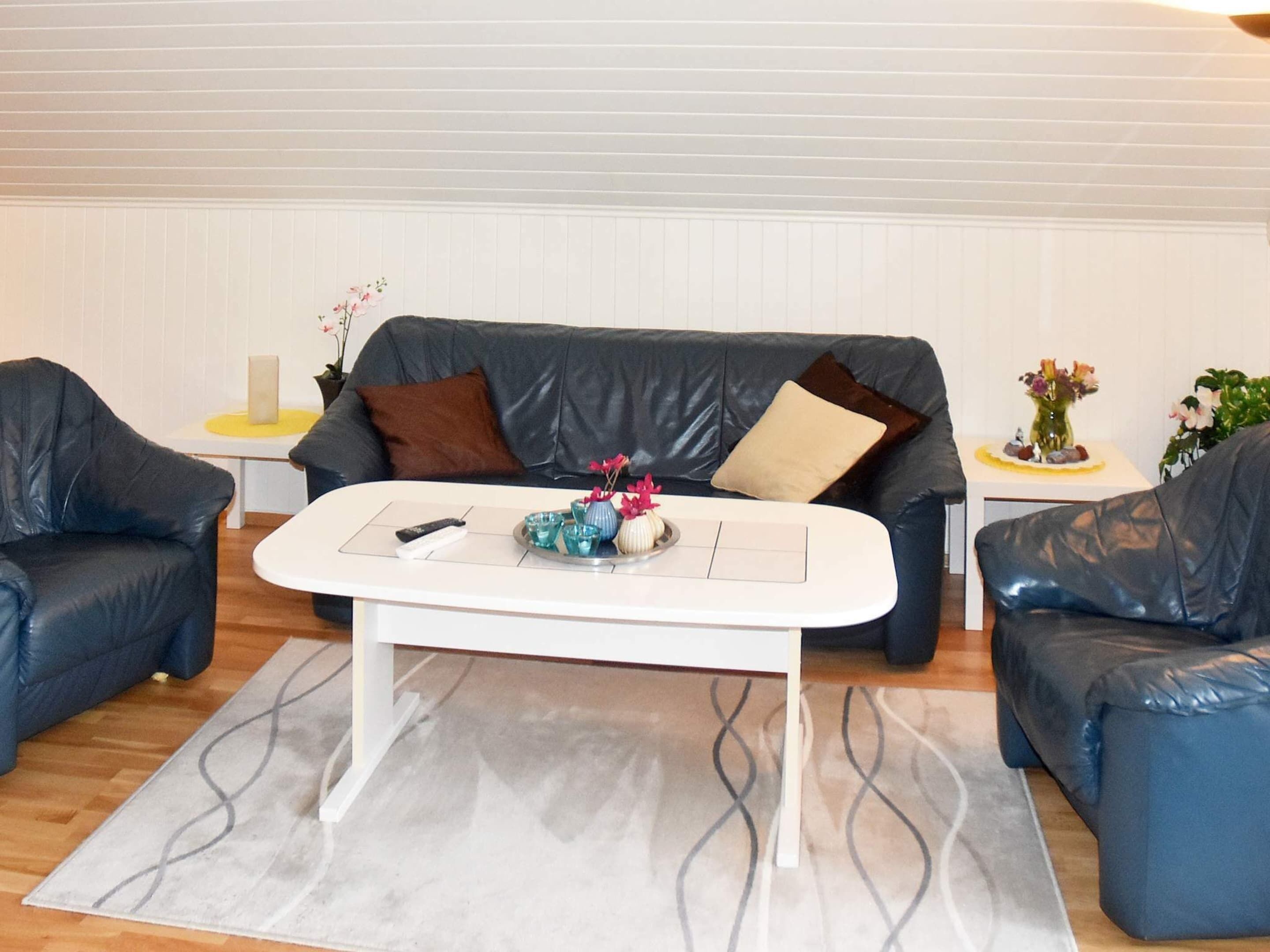 Un salon avec une table basse blanche, deux canapés en cuir bleu et un tapis à motifs gris.