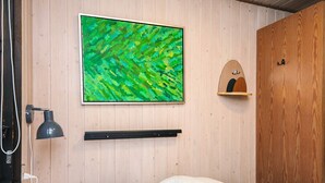 A bedroom with a bed, a wall-mounted TV, a bedside lamp, and a wooden wardrobe.