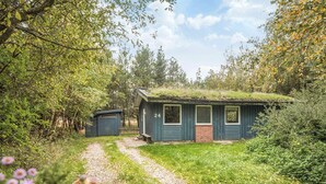 A rustic cabin with a thatched roof, a small porch, and a number 24 sign.