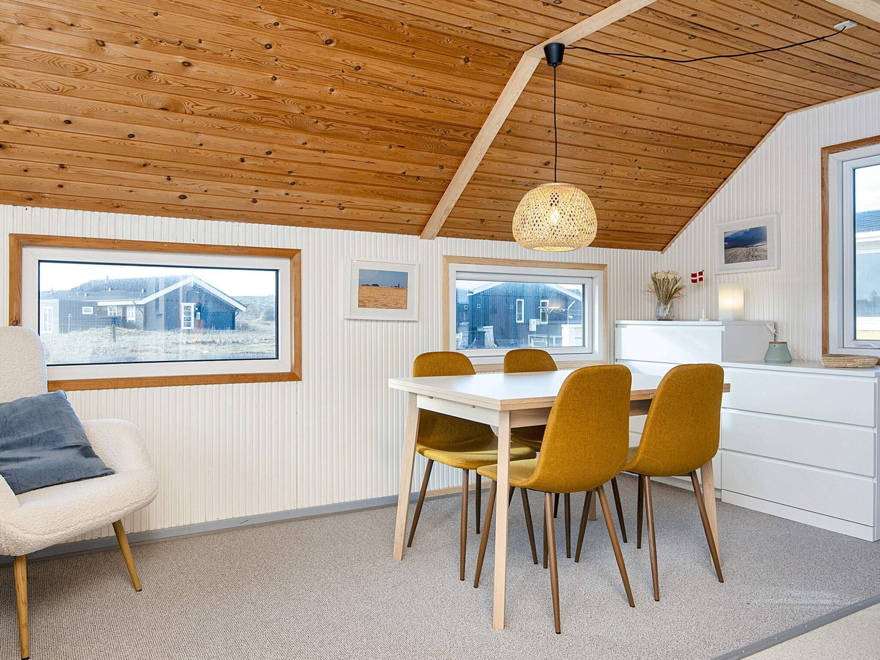 A dining area with a table, chairs, and a hanging light fixture.