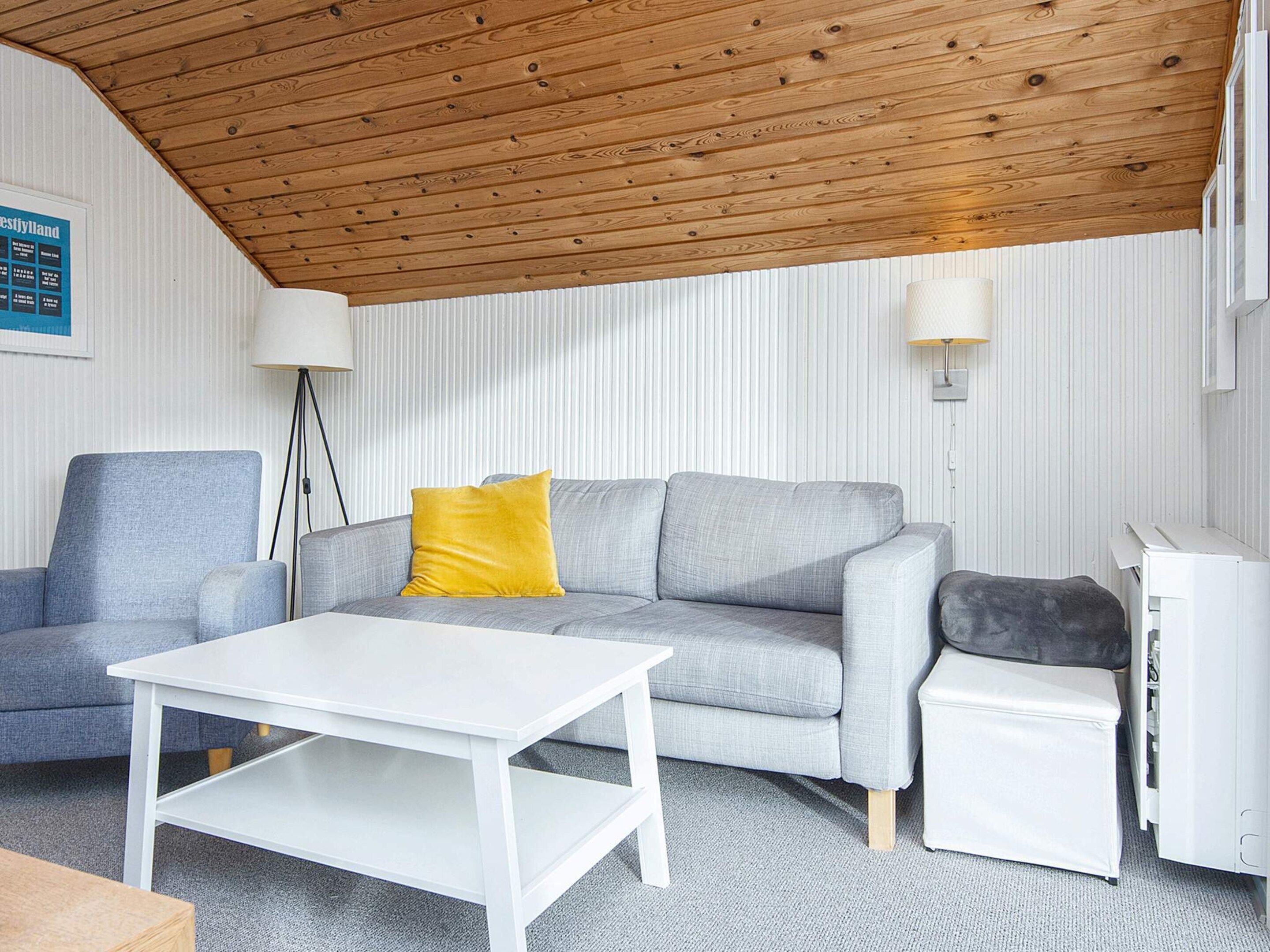 A living room with a grey sofa, a white coffee table, a lamp, and a white cabinet.