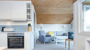 A compact living space with a kitchenette, a sofa, a coffee table, and a television. - 4 Person Holiday Home in Lemvig (Lemvig)