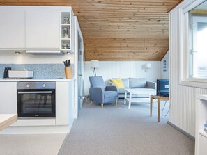A compact living space with a kitchenette, a sofa, a coffee table, and a television.