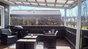 A covered outdoor seating area with wicker furniture, a grill, and a lantern. - 6 Person Holiday Home in Hadsund (Hadsund)