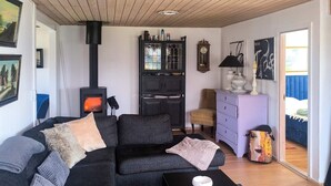 A cozy living room with a sofa, a table, a cabinet, a clock, and a fireplace. - 6 Person Holiday Home in Hadsund (Hadsund)