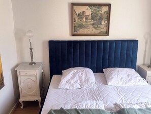 A bedroom with a large bed, a nightstand, a lamp, and a painting on the wall. - 6 Person Holiday Home in Hadsund (Hadsund)