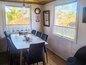 A dining area with a white table, six chairs, a clock, and framed pictures on the wall. - 6 Person Holiday Home in Hadsund (Hadsund)