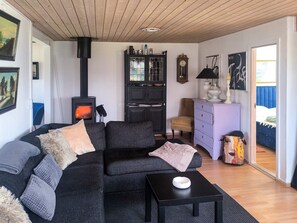 A cozy living room with a sofa, a table, a cabinet, a clock, and a fireplace. - 6 Person Holiday Home in Hadsund (Hadsund)