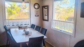 A dining area with a white table, six chairs, a clock, and framed pictures on the wall. - 6 Person Holiday Home in Hadsund (Hadsund)