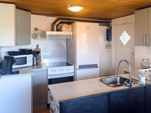 Une cuisine compacte équipée d’un four à micro-ondes, d’une cuisinière, d’un évier et de placards.