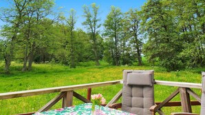 An outdoor seating area with a table covered in a floral tablecloth, surrounded by wooden chairs and a cushioned bench. - 4 Person Holiday Home in Gotene (Götene)