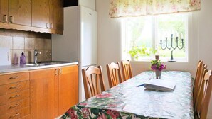 A kitchen with wooden cabinets, a white refrigerator, a sink, and a window with a floral valance. - 4 Person Holiday Home in Gotene (Götene)