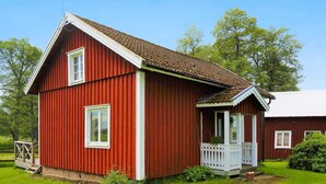 A red wooden house with a white porch and a small garden. - 4 Person Holiday Home in Gotene (Götene)