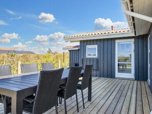 En terrass med ett bord och stolar, ett fönster och en dörr.