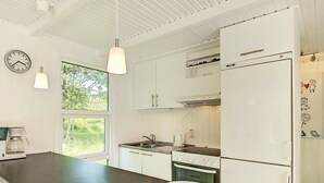 A modern kitchen with white cabinetry, a black countertop, a stove, and a refrigerator. - Serene Holiday Home in Bornholm With Terrace (Akirkeby)