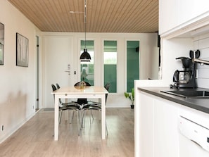 A modern kitchen with a wooden ceiling, white cabinetry, and a black coffee maker.