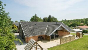 A modern house with a covered patio, a play area, and a slide. - Elegant Holiday Home in Jutland With Sauna (Horsens)