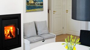 Tunnelmallinen olohuone, jossa on takka, raidallinen sohva, taulu ja lamppu.