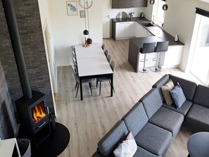 A modern living space with a fireplace, a dining area, a kitchen, and a sofa. - 5 Star Holiday Home in Sydals (Sydals)