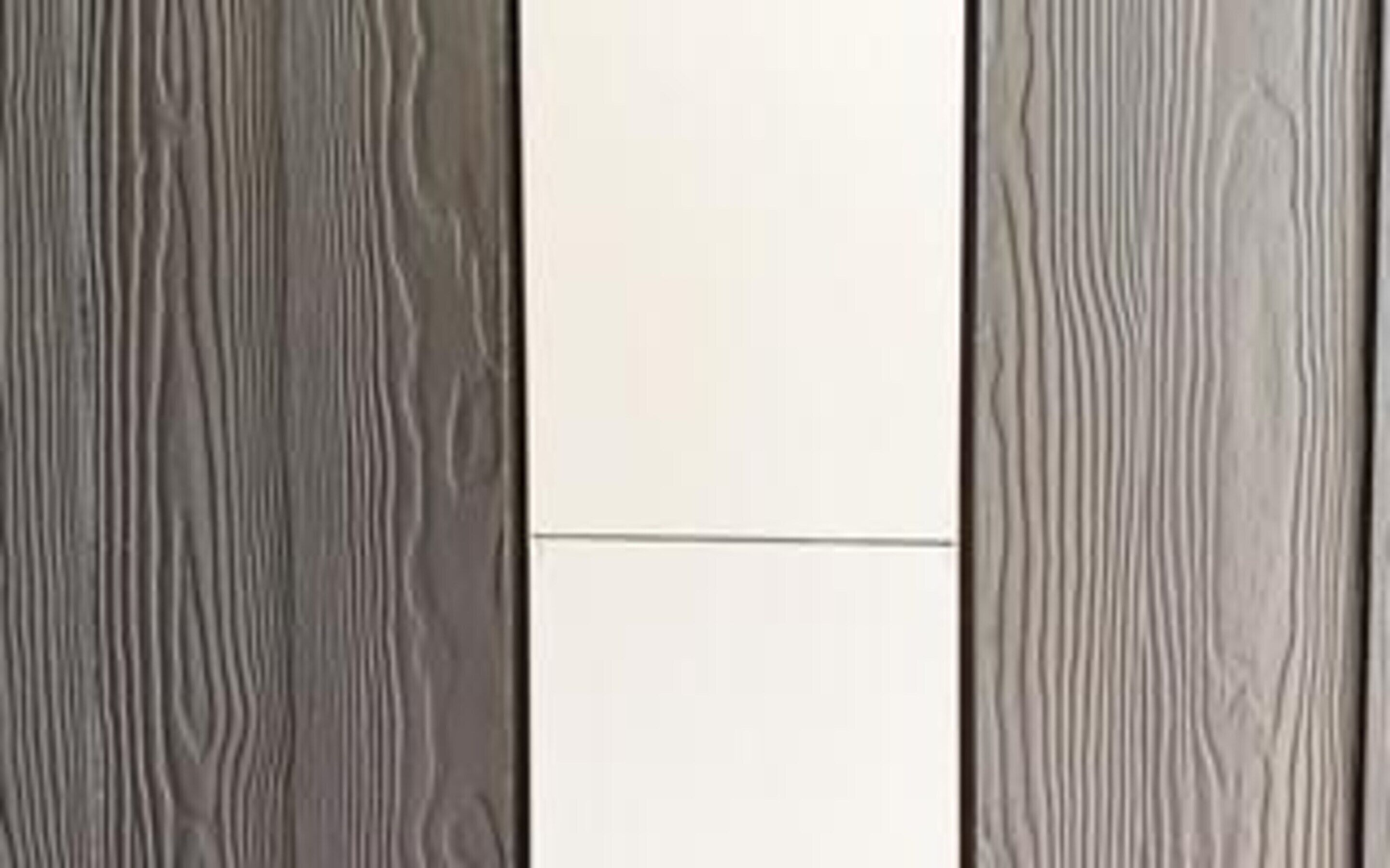Una habitación con pared de paneles de madera y un panel central blanco.