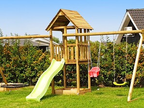 A wooden play structure with a slide and swings in a grassy yard. - 5 Star Holiday Home in Sydals (Sydals)