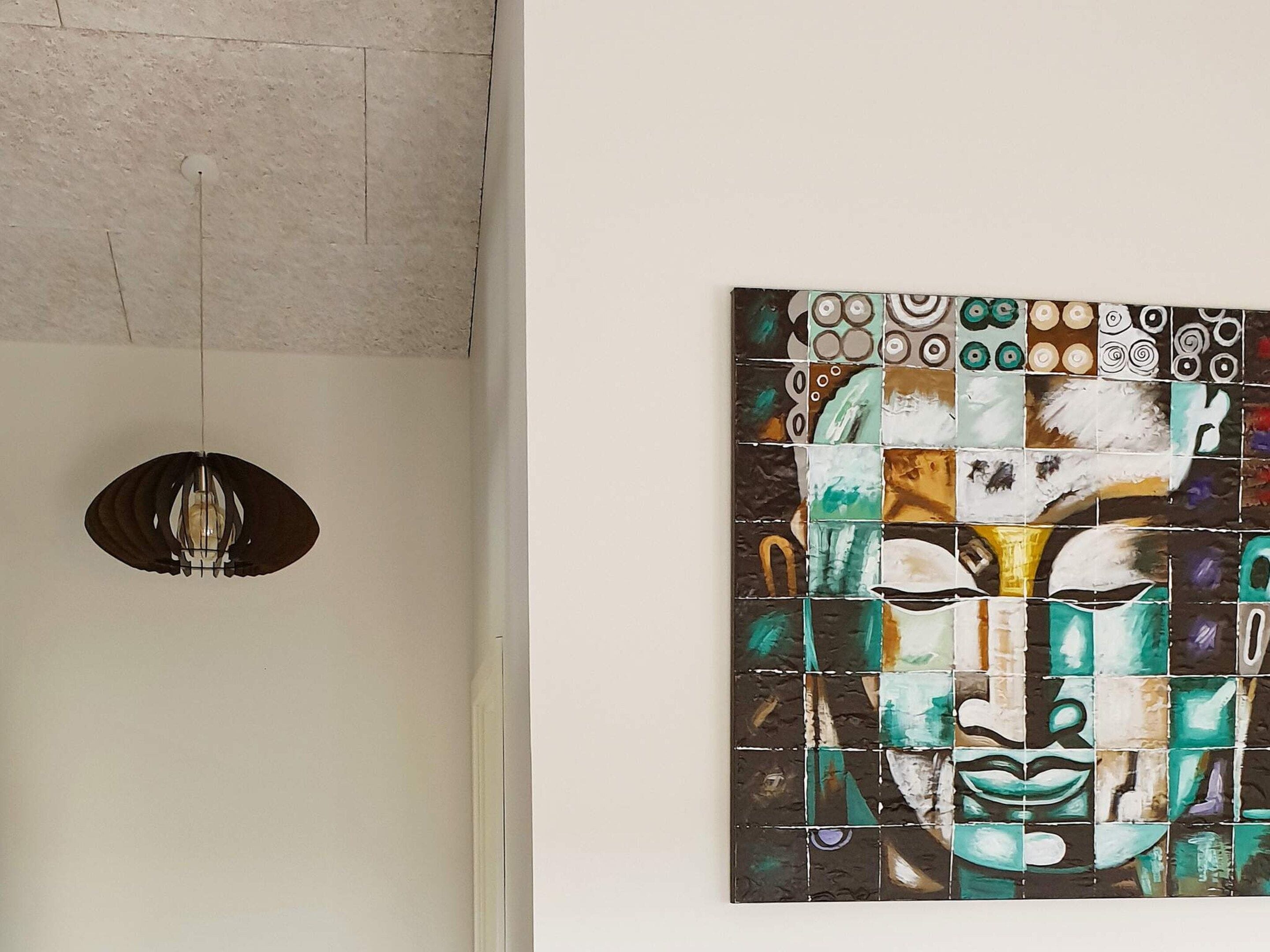 A wall with a mosaic artwork and a hanging pendant light.