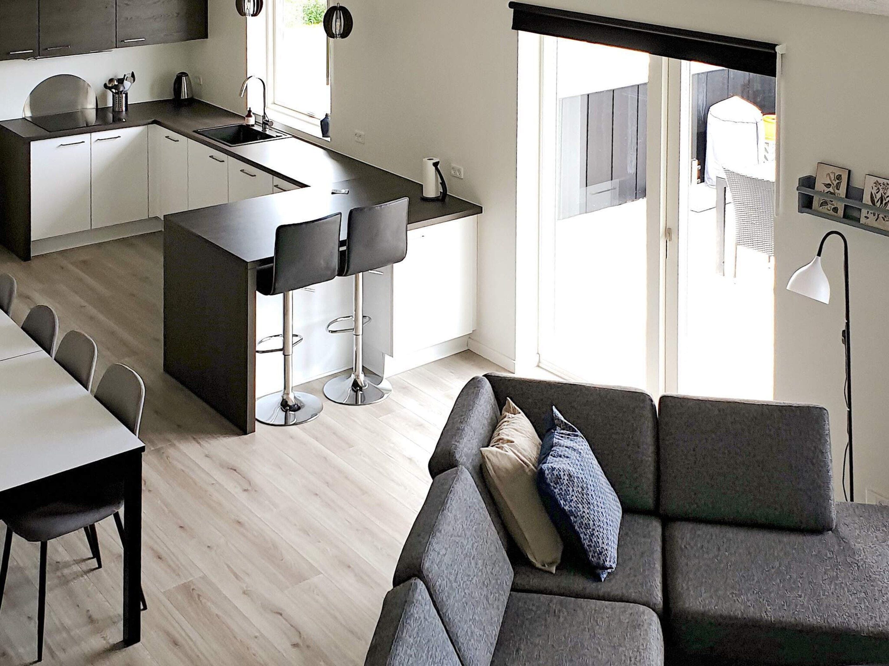 Une cuisine moderne dotée d’un îlot central, de tabourets de bar et d’un coin repas avec une table et des chaises.