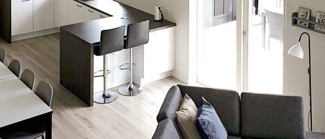 A modern kitchen with a central island, bar stools, and a dining area with a table and chairs.