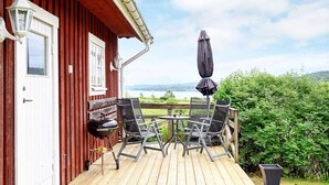 A wooden deck with outdoor furniture, a flag, and a view of a lake. - 4 Person Holiday Home in Arjang (Årjäng)