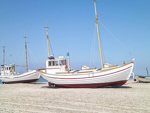 Een rij boten afgemeerd aan een zandstrand.
