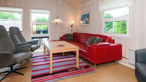 A cozy room with a red sofa, a wooden coffee table, and striped rugs. - 6 Person Holiday Home in Hadsund (Hadsund)
