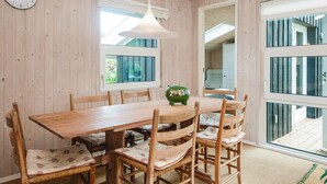 A wooden dining room with a table and chairs, a hanging light fixture, and a clock on the wall. - 6 Person Holiday Home in Hadsund (Hadsund)