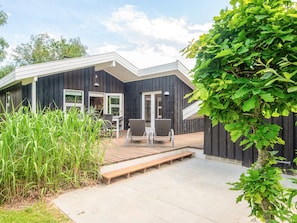 A modern house with a deck, two chairs, and a small table. - 6 Person Holiday Home in Hadsund (Hadsund)