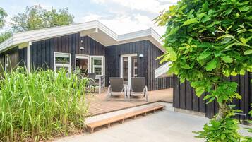 Et moderne hus med terrasse, udendørs møbler og have.
