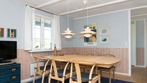 A dining area with a wooden table and chairs, a television on a dresser, and artwork on the walls. - Premium Holiday Home in FanÃ¸ near Beach (Fano)